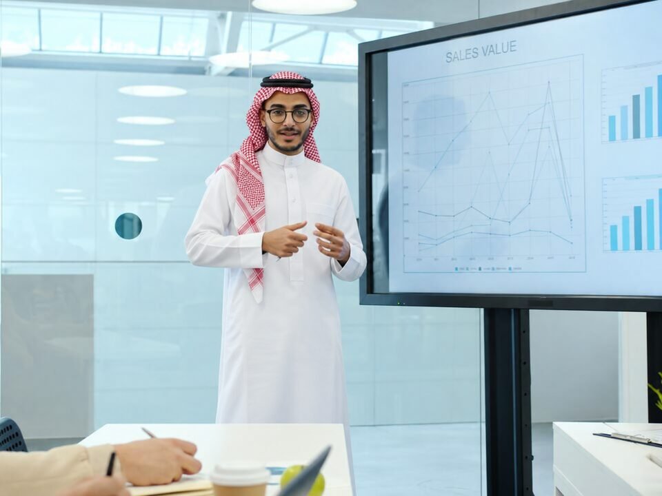 مدرّب بالزي السعودي يعرض مؤشرات على شاشة أمام متدربين