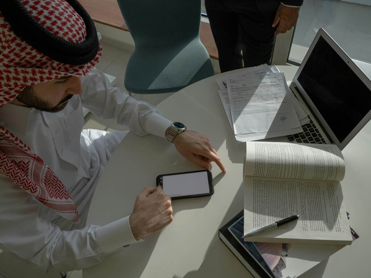 مختص سعودي يعمل على مستندات وجهاز لوحي في اجتماع عمل